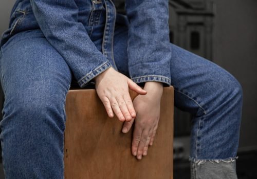 Close-up, a woman in a denim suit plays, sitting on the cajon.